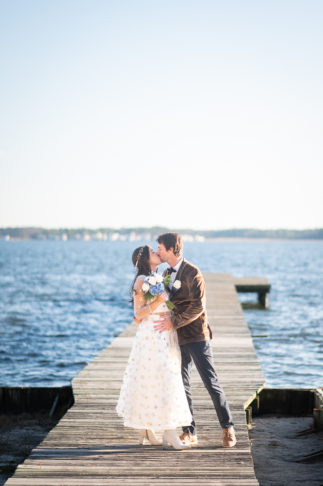 bride and groom kissing on dock after beach wedding ceremony