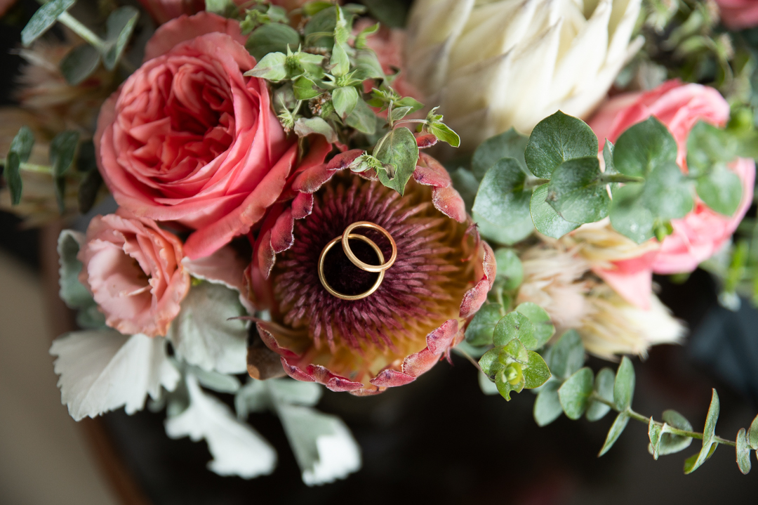 A Philadelphia wedding bouquet with wedding bands laying inside a protea bloom